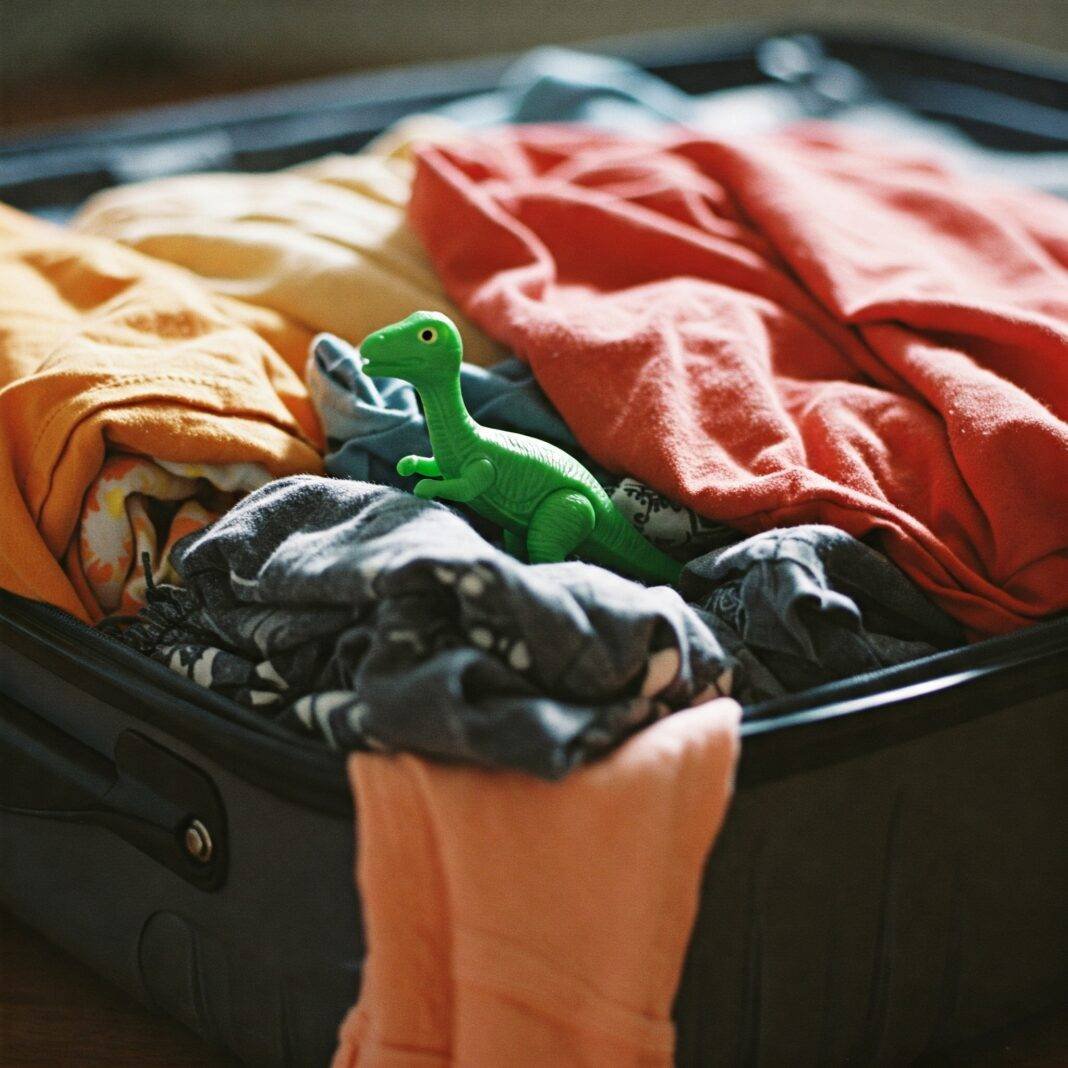 Messy suitcase packing with dinosaur